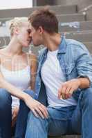 Hip young couple in denim sitting on steps about to kiss