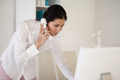 Casual asian businesswoman answering the telephone