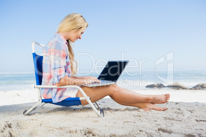 Woman sitting on beach using her laptop