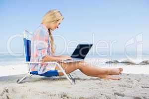 Woman sitting on beach using her laptop