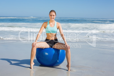 Fit woman sitting on exercise ball at the beach