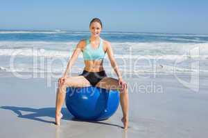 Fit woman sitting on exercise ball at the beach