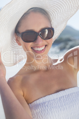 Pretty blonde in white dress and sunhat on the beach