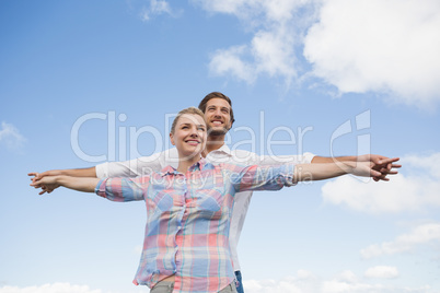 Happy couple standing outside with arms stretched