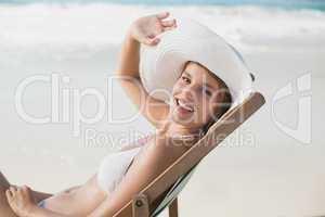 Smiling woman relaxing in deck chair on the beach