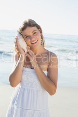 Beautiful blonde in white sundress on the beach listening to con