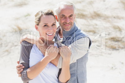 Happy hugging couple on the beach looking at camera