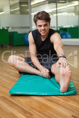 Fit smiling man warming up in fitness studio