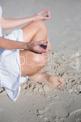 Woman in white dress meditating on the beach