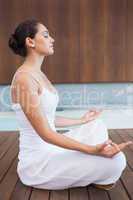 Content brunette in white sitting in lotus pose