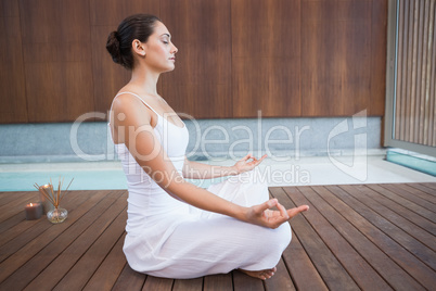 Peaceful brunette in white sitting in lotus pose