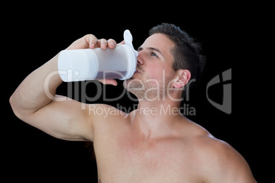 Happy muscular man drinking protein drink