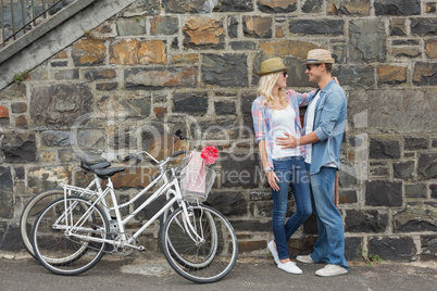 Hip young couple hugging by brick wall with their bikes