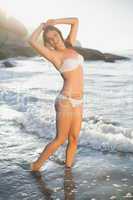Beautiful smiling blonde in white bikini at the beach with wet h