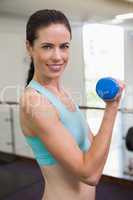 Smiling woman lifting blue dumbbell