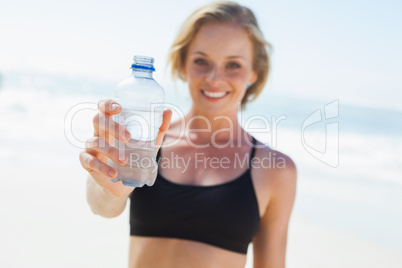 Fit blonde drinking water on the beach