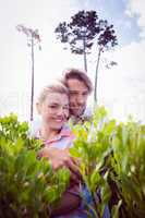 Smiling couple embracing outside among the bushes