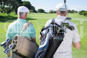 Golfer friends walking holding their golf bags