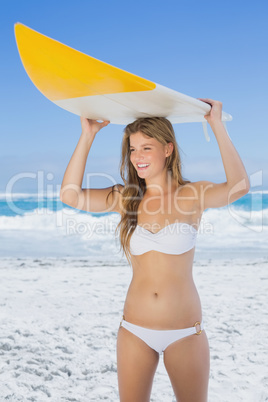 Pretty surfer girl holding her surfboard on the beach