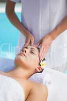 Tranquil brunette getting a head massage poolside