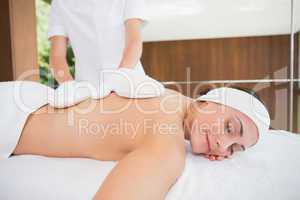 Beauty therapist rubbing womans back with heated mitts