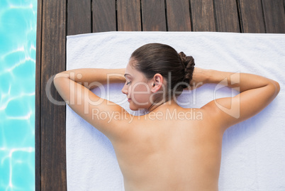Tranquil brunette lying on towel poolside