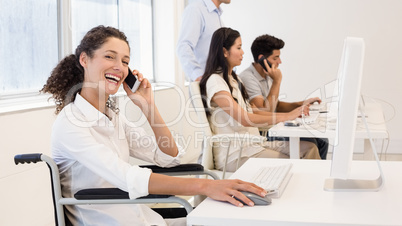 Casual businesswoman in wheelchair on the phone smiling at camer