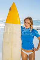 Blonde happy surfer holding her board on the beach