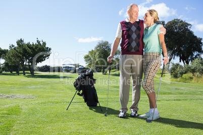 Golfing couple standing smiling at each other