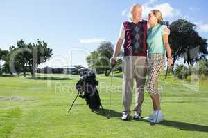 Golfing couple standing smiling at each other