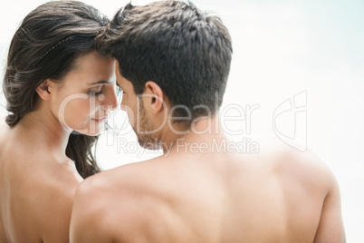 Attractive couple sitting poolside smiling