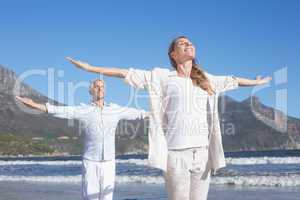 Happy couple standing with arms outstretched at the beach