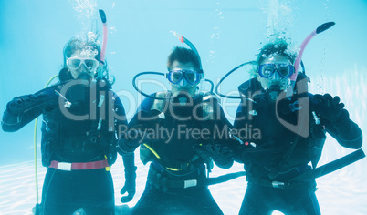 Friends on scuba training submerged in swimming pool making ok s