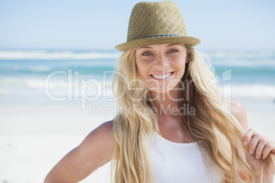 Stylish blonde smiling at camera on the beach