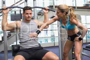 Bodybuilder using weight machine for arms with encouraging train