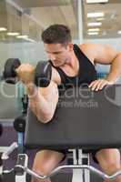 Focused bodybuilder lifting heavy black dumbbell