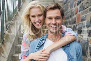 Hip young couple sitting on steps smiling at camera