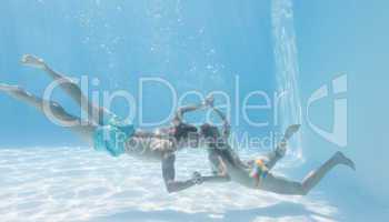 Cute couple holding hands underwater in the swimming pool