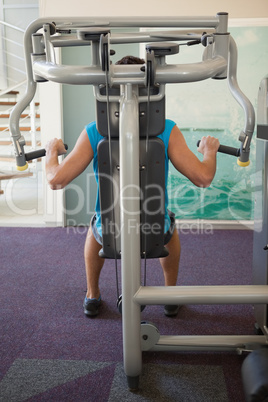 Focused man using weights machine for arms