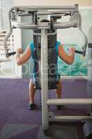 Focused man using weights machine for arms