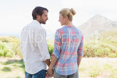 Cute couple standing hand in hand smiling at each other