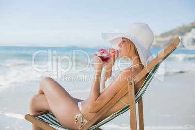 Smiling woman relaxing in deck chair with cocktail