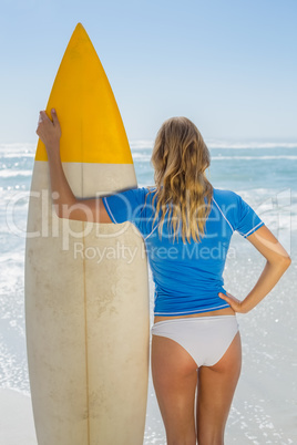 Blonde surfer holding her board on the beach