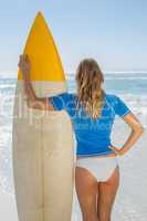 Blonde surfer holding her board on the beach
