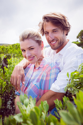 Smiling couple embracing outside among the bushes
