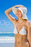 Smiling blonde in white bikini and sunhat on the beach