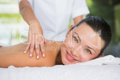 Content brunette getting a back massage smiling at camera