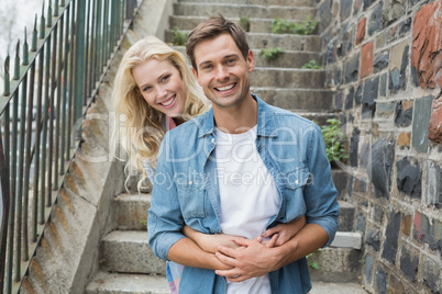 Hip young couple sitting on steps smiling at camera