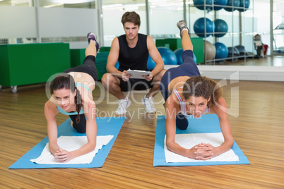 Fit women working out together in studio with trainer