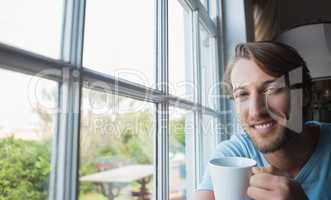 Smiling man sitting by the window having coffee